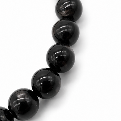 Single hypersthene bracelet on soft off-white surface, natural light showing moonlit sheen