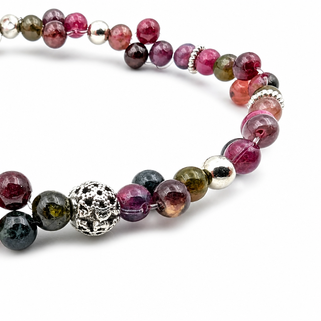 Close-up of the openwork silver filigree focal bead between deep green and magenta tourmaline beads