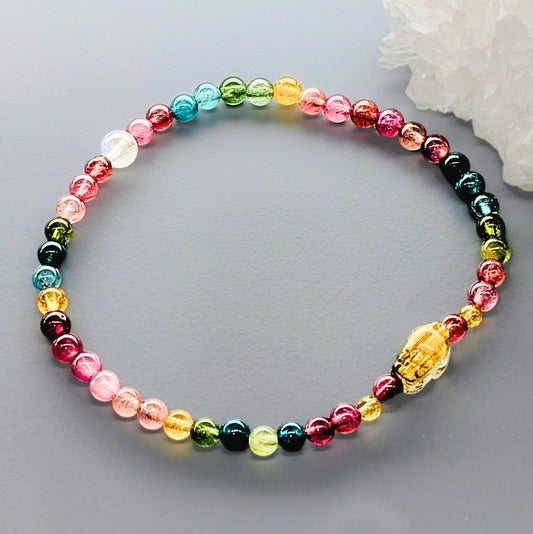 AuraLuneCrystal Triple Abundance bracelet with a golden rutile pixiu charm, colorful rainbow tourmaline, and blue flash moonstone beads.