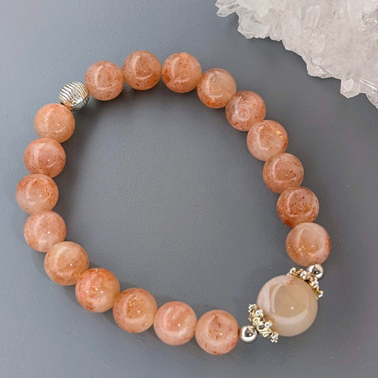 AuraLuneCrystal Radiant Bloom bracelet featuring glittering orange Sunstone beads and a central Flower Agate with natural blossom patterns.