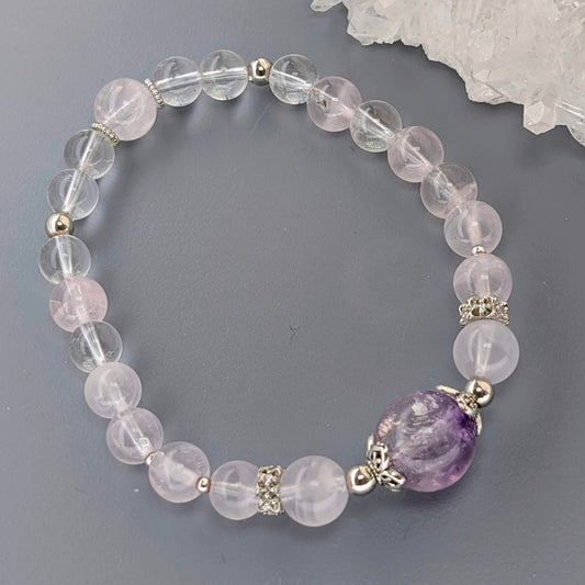 AuraLuneCrystal Celestial Heart Bloom bracelet featuring a large purple Super 7 bead with silver butterfly caps, soft pink rose quartz, and clear quartz.