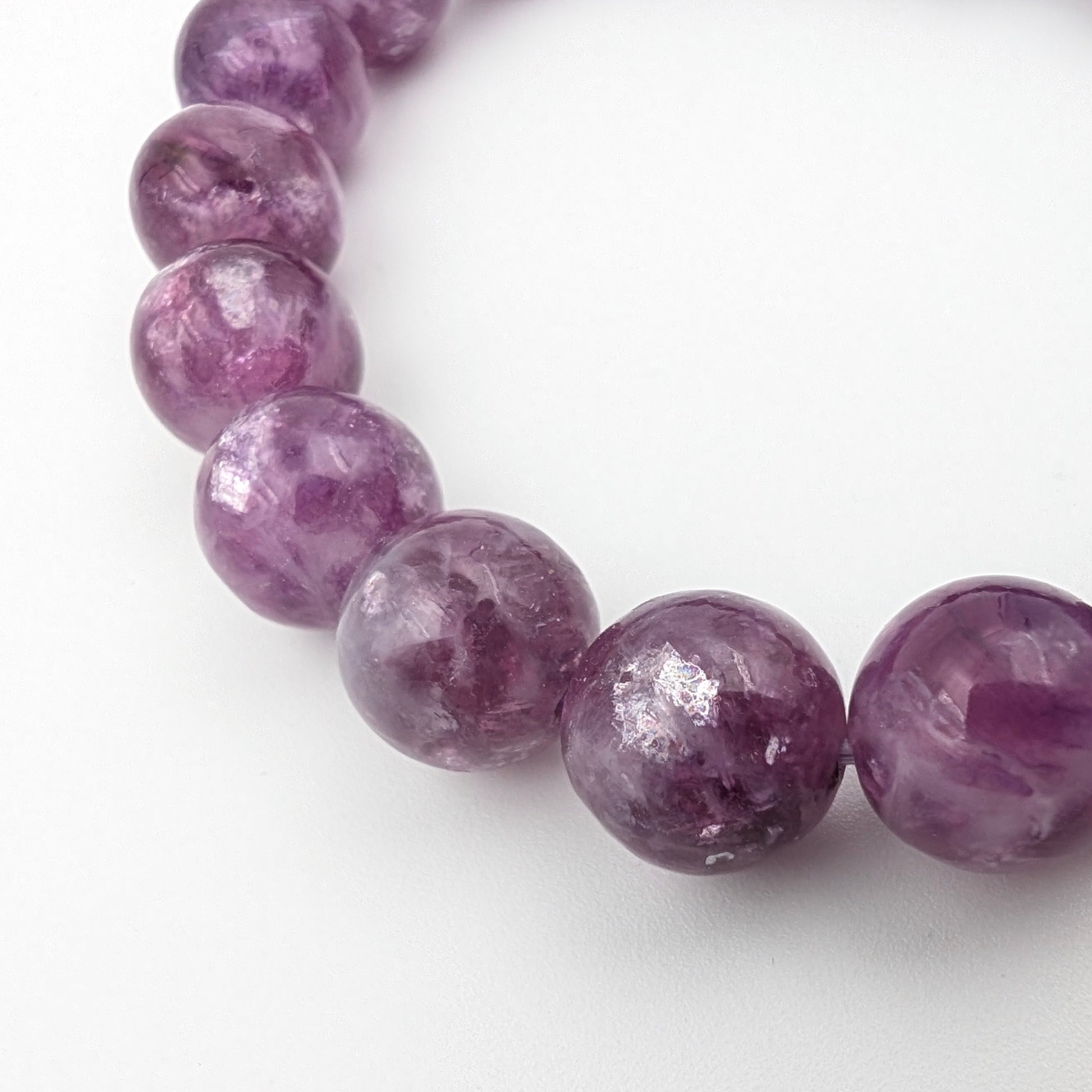 Lepidolite bracelet catching light across its pearly bead surfaces