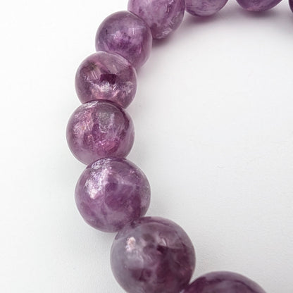 Side view of a violet lepidolite stretch bracelet on white
