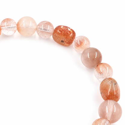 Red Sunstone and Rabbit Hair Quartz bracelet resting flat on a pale surface