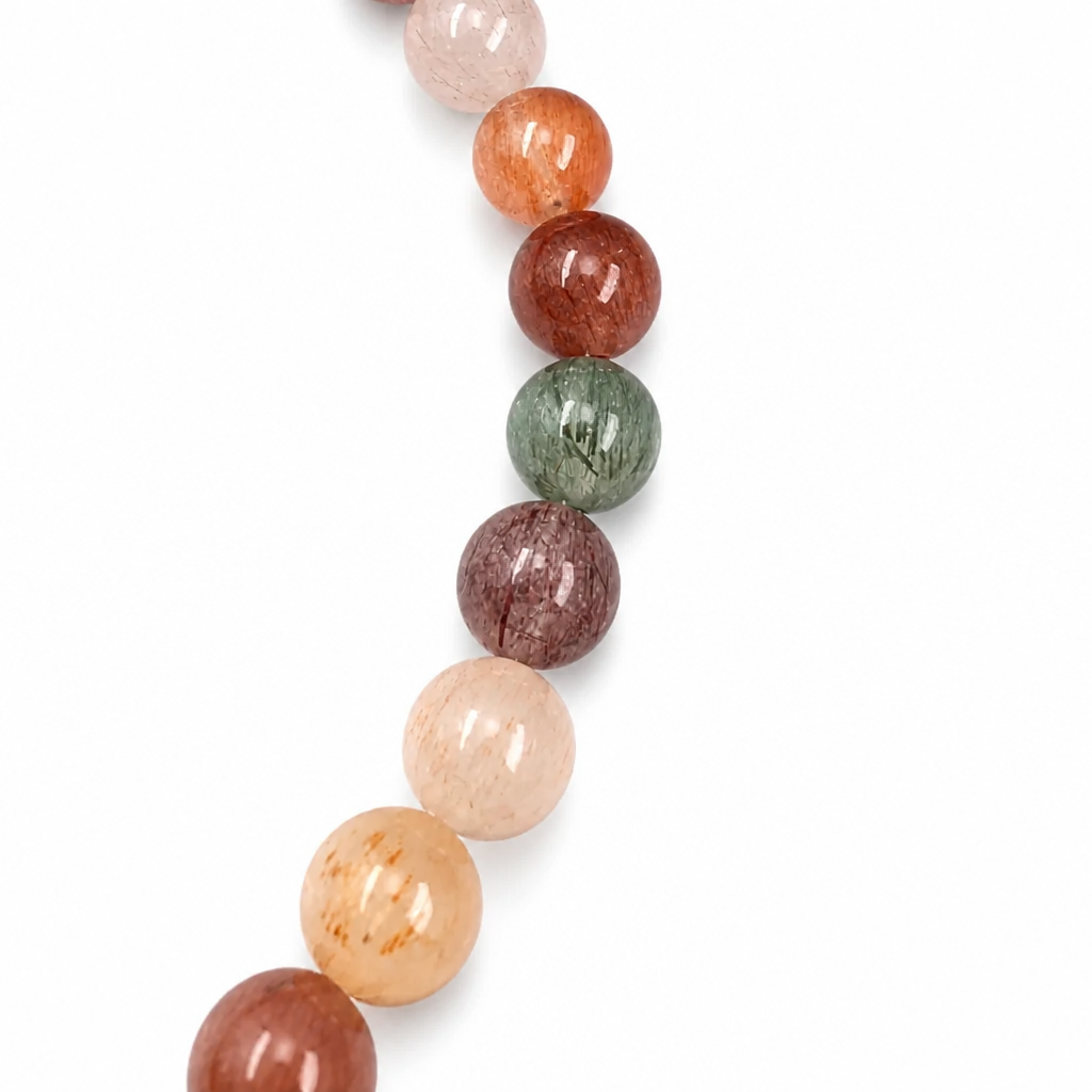 Side view of the 6mm Rabbit Hair Quartz bracelet on a pale surface