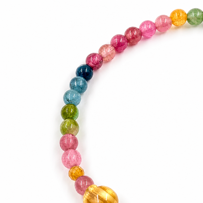 Rainbow tourmaline bracelet with Pixiu charm resting flat on white background