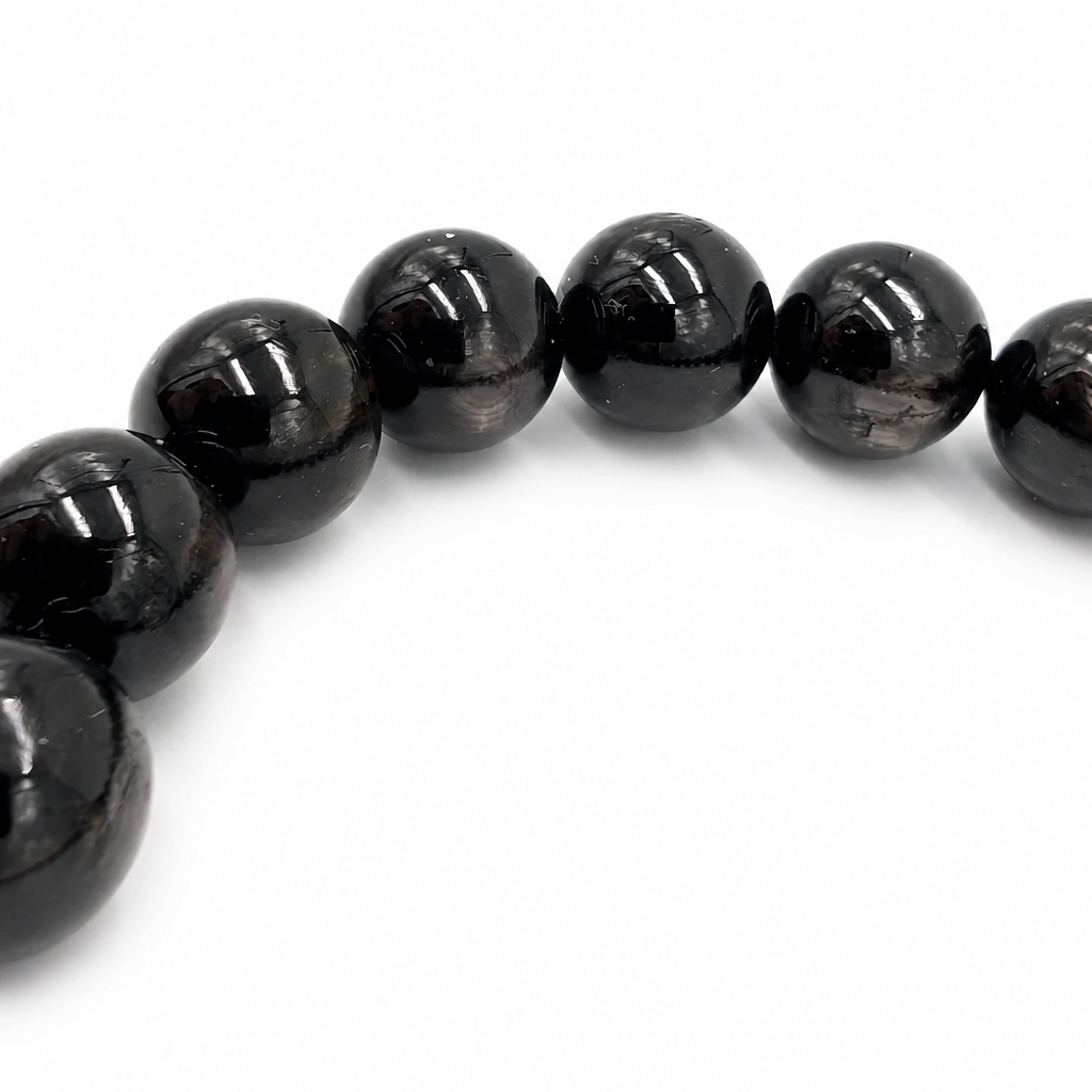 Angled view of the Hypersthene Schiller bracelet catching light across each bead