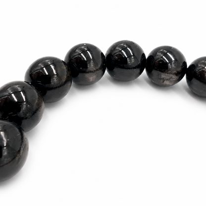 Angled view of the Hypersthene Schiller bracelet catching light across each bead