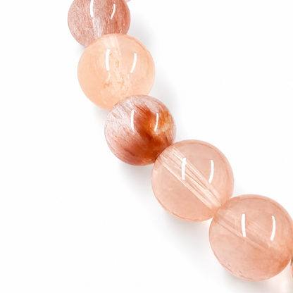 Sunstone and Rabbit Hair Quartz bracelet resting flat on a pale surface