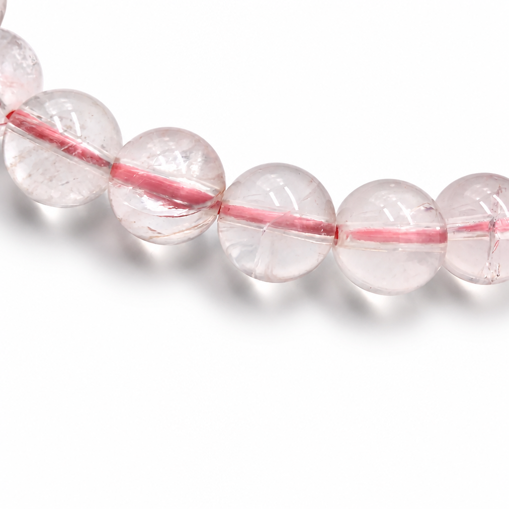 Detail of jelly-grade clarity in individual Madagascar Ice Rose Quartz beads on white surface