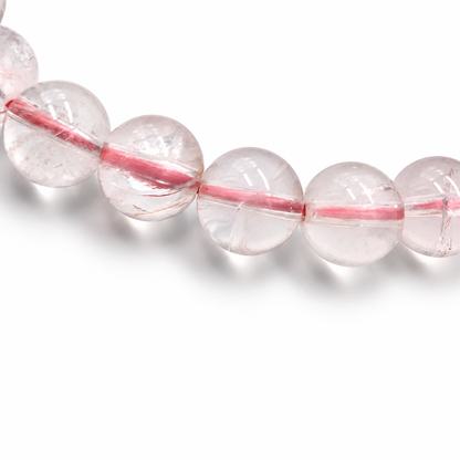 Detail of jelly-grade clarity in individual Madagascar Ice Rose Quartz beads on white surface