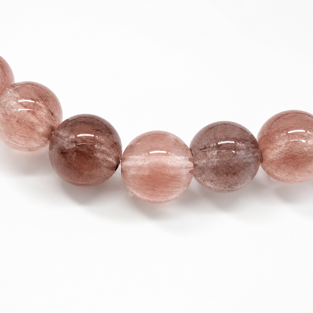 Coral and vermilion fibres catching light inside a quartz bead