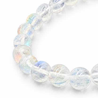 Side view of the 6mm Madagascar Rainbow Moonstone bracelet on a pale surface